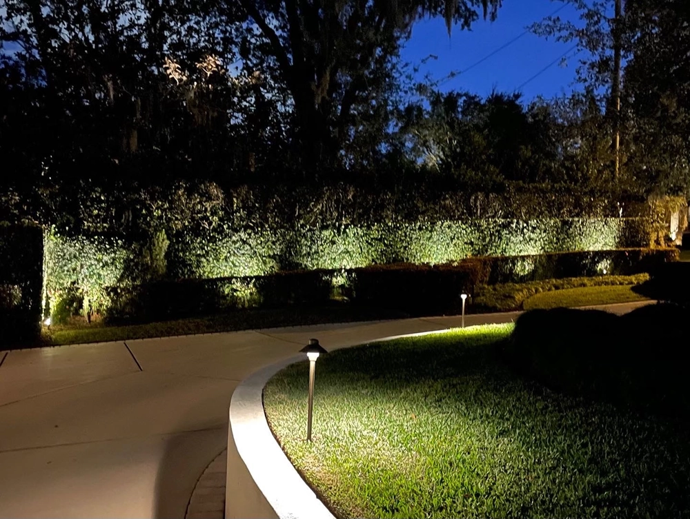 Elegant LED safety lighting in Central Florida highlighting a curved driveway and trimmed hedges